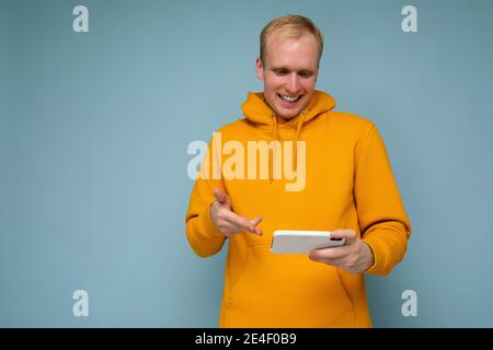young man holding in hand and using mobile phone communicating online looking at gadjet screen Stock Photo