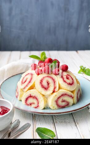 Refreshing Charlotte royale cake filled with raspberry jam and decorated with fresh berries on rustic wooden table Stock Photo