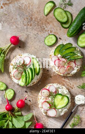 Sandwiches crispbread with ricotta, radish and fresh cucumber on a light or slate countertop. Top view flat lay background. Copy space. Stock Photo