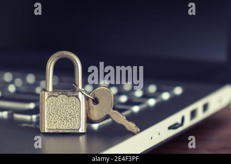 Padlock and keys on a laptop keyboard on a wooden desktop. Computer security concept. Copy space. Stock Photo