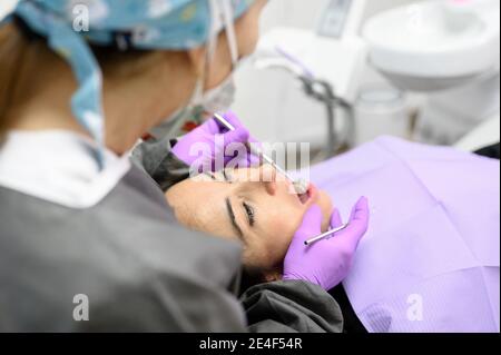 Dentist hygienist making oral hygienic cleaning in dentistry for young woman. Using professional electrical equipment dental drill machine to brush teeth in dentistry. High quality photo. Stock Photo