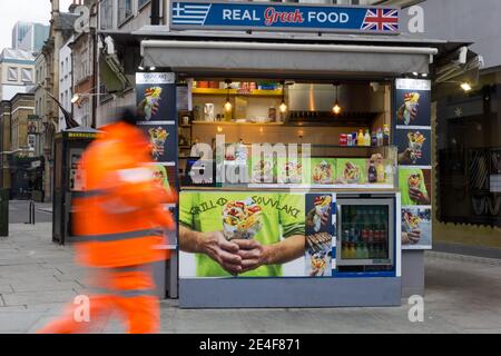 a man walk past Real greek Food store take away on oxford street London Stock Photo