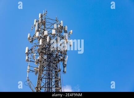The top of a cell phone tower against a blue sky Stock Photo