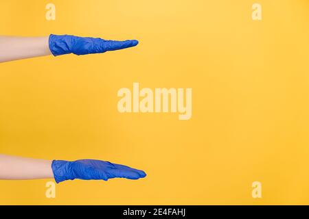 Female hands in protective blue gloves shows width of something pretends holding item or thing, demonstrates size. Body language concept Stock Photo