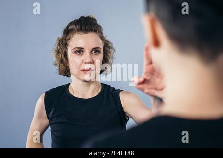 Coach teaches athlete to hit kick. Strong female martial arts athletes in their taekwon-do training. Two young women instructor and student practicing Stock Photo