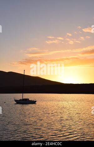 The sun setting behind a sailboat on the harbor at Molino Viejo, near San Quintin, Baja California, Mexico Stock Photo