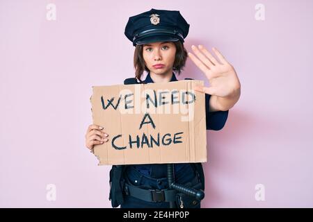 Young beautiful woman wearing police uniform holding we need a change banner with open hand doing stop sign with serious and confident expression, def Stock Photo