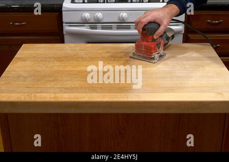 Refinishing a kitchen counter using an electric sander Stock Photo