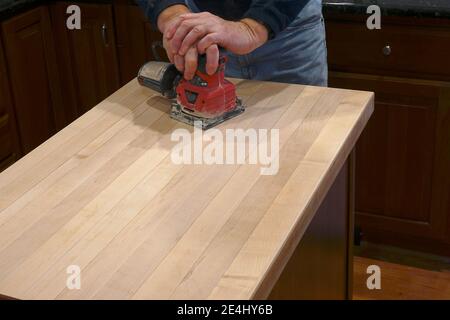 Using an electric sander to refinish a counter top Stock Photo