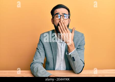 Young hispanic man working at the office bored yawning tired covering mouth with hand. restless and sleepiness. Stock Photo