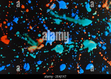 Speckled paint of different colors on a black background Stock Photo