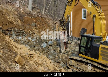 Tracked excavator with the hydraulic hammer in a working on smashing rock a road of stones Stock Photo