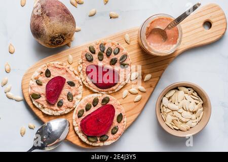 Crispy puffed rice cakes on table hummus spread and tomato and beet vegetables and sesame pumpkin seeds on the table - top view on healthy vegetarian Stock Photo