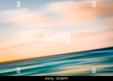 Pink sunset over the sea abstract background. Turquoise colored water and beautiful cloudy sky, long exposure, motion blur Stock Photo