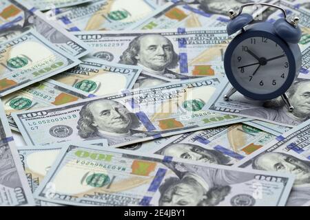 Time - money. Alarm clock on the stack of one hundred american dollars bills. Credit, deposit and mortgage concept. Stock Photo