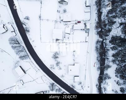 Top view of the road near the snow-covered houses and the mountain river flowing near them. Stock Photo