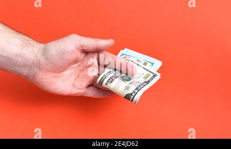 Hand holding folded money usa dollar on red background Stock Photo