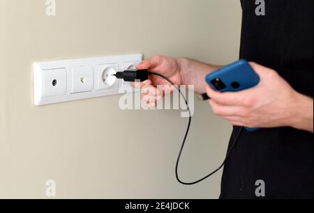 Hand inserting smarthone charger into a socket Stock Photo