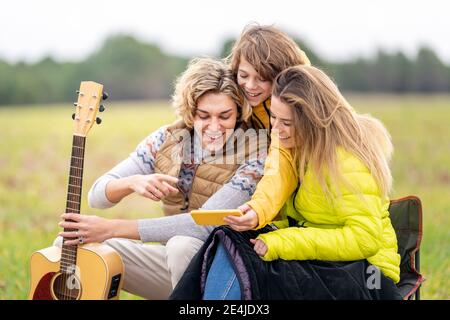 Three siblings using smart phone outdoors during hike Stock Photo