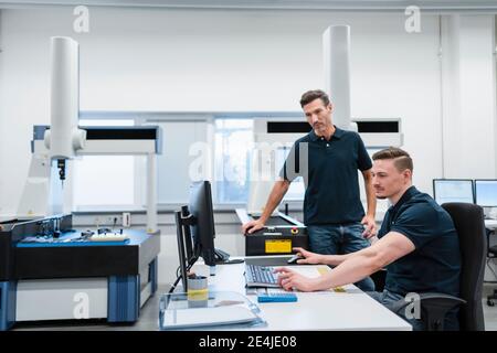 Male technician with colleague using computer in industry office Stock Photo