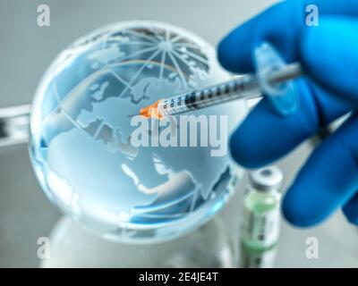Close-up of doctor inserting injection in glass globe on table Stock Photo