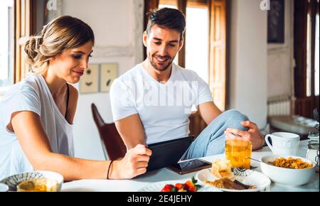 Young couple watching tablet while having breakfast at home Stock Photo
