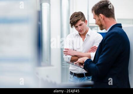 Male professionals discussing with engineer over digital tablet in factory Stock Photo