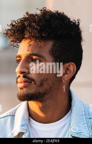 Close-up of thoughtful young man wearing cross shaped earring Stock Photo