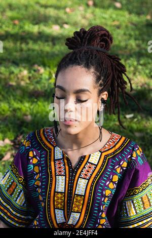 Young woman meditating while practicing yoga at park on sunny day Stock Photo