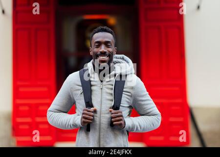 Young man carrying backpack while standing outdoors Stock Photo