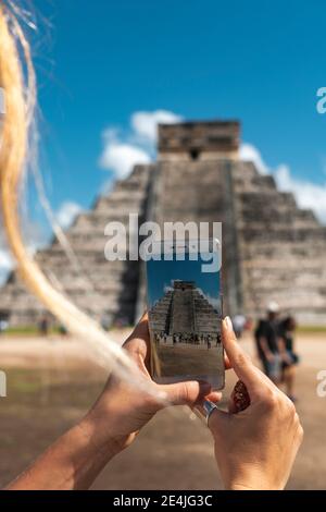 Mexico, Yucatan, Chichen Itza, Hands of female tourist taking smart phone photos of Temple Of Kukulcan Stock Photo