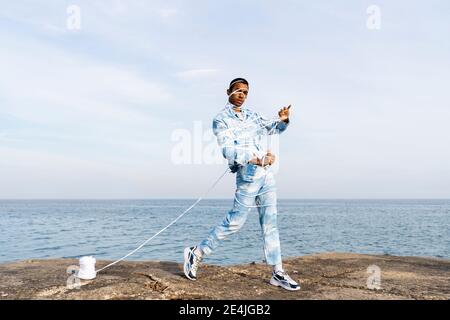 Man trapped in rope struggling to set free while standing against sea Stock Photo