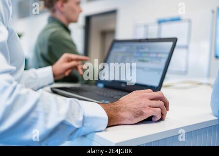 Businessman using laptop while working with coworker at office Stock Photo