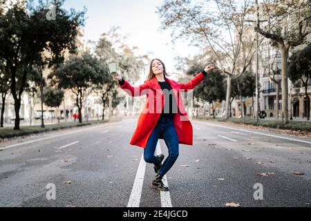 Fashionable woman with coffee cup dancing on street Stock Photo
