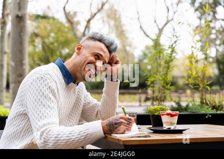 Man laughing while writing in book at sidewalk cafe Stock Photo