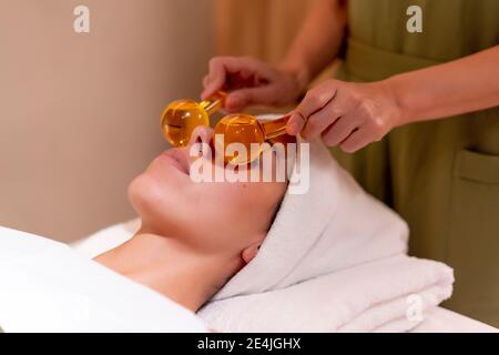 Beautician holding glass globes on female customer's face at health spa