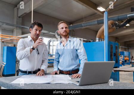 Two carpenters talking over documents in production hall Stock Photo
