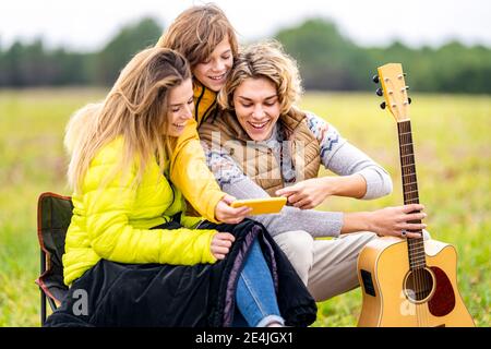 Three siblings using smart phone outdoors during hike Stock Photo