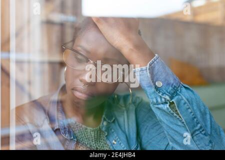 Sad woman looking through window Stock Photo