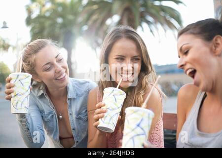 Carefree friends drinking chilled drinks at beach during vacation Stock Photo