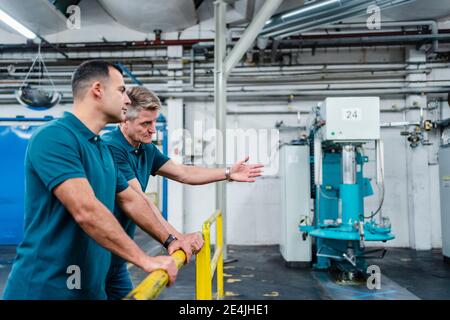 Male technicians discussing while working in factory Stock Photo