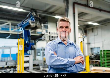 Smiling supervisor with arms crossed looking away in industry Stock Photo