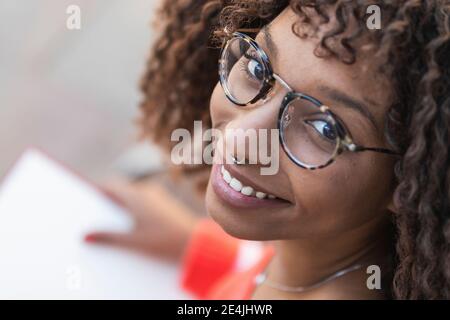 Smiling afro woman in eyeglasses with book Stock Photo