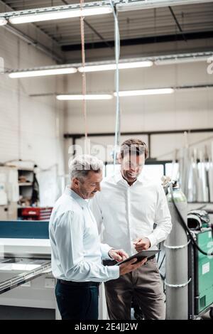 Professionals using digital tablet while working at industry Stock Photo