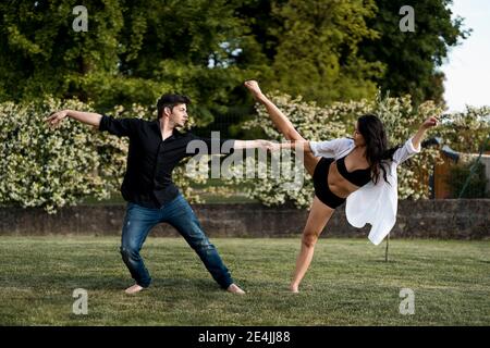 Dancer couple holding hand while dancing over grass in back yard Stock Photo