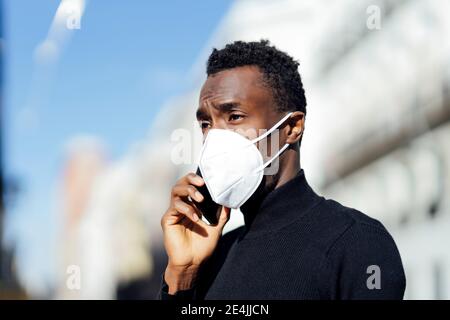 Young man talking on mobile phone while standing outdoors Stock Photo