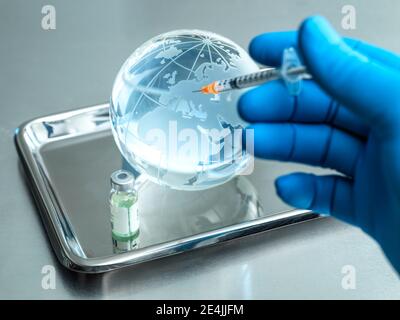 Doctor injecting injection in glass globe by vial on table Stock Photo