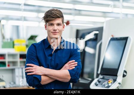 Handsome young male entrepreneur with arms crossed in industry Stock Photo