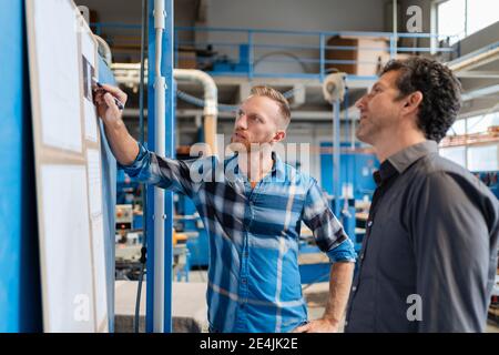 Two carpenters talking over documents in production hall Stock Photo