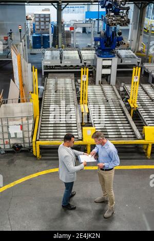 Businessman and manager discussing over document while having meeting in factory Stock Photo
